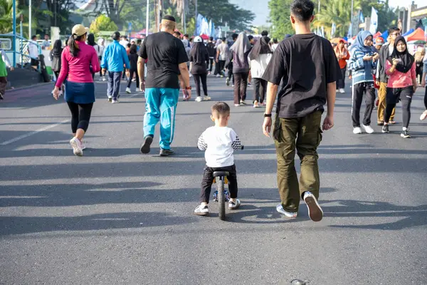 Yetişkinlerle Bisiklete Binen Genç Bir Çocuk Arka planda Yürüyor