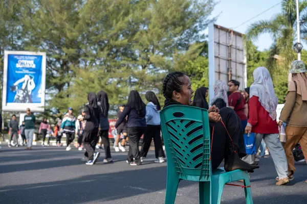 Siyah Giysili Kadın Halka açık bir alanda Yeşil Sandalyede Oturuyor