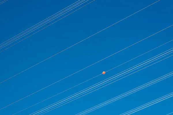 stock image High voltage power lines with orange air warning ball in front of pure blue sky