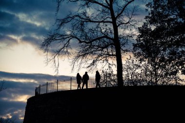 Akşam üzeri, Sparrenburg Kalesi 'nde insanlar yürür. Siluetleri, ağaçlar ve kale duvarları ağır bulutlu arka planda keskin bir şekilde göze çarpıyor..