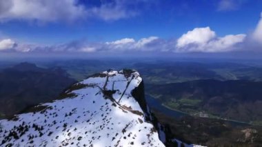 Huzurlu bir nehir ve aşağıdaki yemyeşil vadiye bakan karla kaplı bir dağ sırtı manzarası. Dağ treni. Schafberg, Avusturya. Hiperlapse.