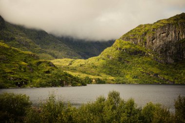 Gölün kenarındaki dingin ve sakin bir hytte heybetli dağların ve gür yeşil manzaraların arasına kurulmuştur. Sorvagen, Lofoten Adaları, Norveç.