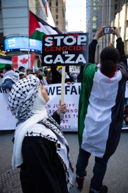 Yaşlı Filistinli kadın, Toronto Ontario Kanada 'daki savaşa karşı Filistin' de düzenlenen protestoda Gazze 'deki soykırımı durdurun diyen bir tabela tutuyor.