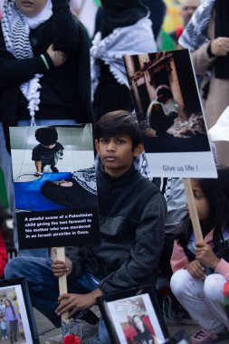 Çocuk, Toronto Ontario Kanada 'da Gazze' deki savaşa karşı Filistin Protestosuna doğru bakan bir tabela tutuyor.