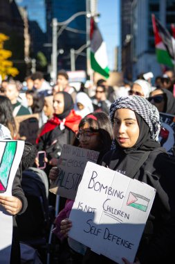 Toronto Ontario Kanada 'sında Gazze' deki savaşa karşı Filistin Protestosu 'nda çocukları bombalamanın meşru müdafaa olmadığını söyleyen bir tabela tutuyor.