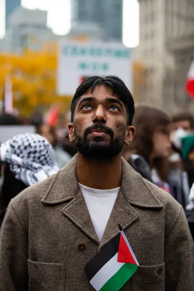 stock image Man wearing a jacket looks to the sky holding a small Palestinian flag at a Palestinian demonstration Toronto Canada against the war in Gaza