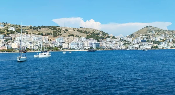 Arnavutluk 'un Saranda limanı, 2023 yazında deniz kıyısında, yelkenli tekneleri heyecan verici bir yolculuk, mavi su ve mavi gökyüzü beklentisiyle demirlemiş durumda.