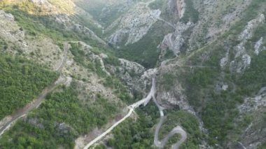 Karadağ, dağların arasında yeşil ormanlarla kaplı İHA uçuşu aralarında dar bir dağ yolundan geçiyor