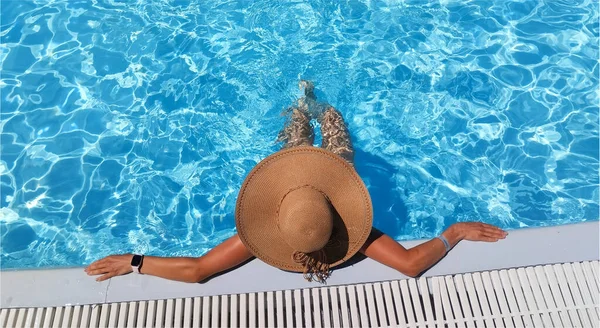 Çimenlik. Havuzda geniş kenarlı şapkalı bir kız.