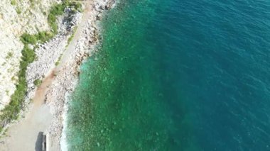İnsansız hava aracı, kayalık bir sahil boyunca uçan drone, kayalık bir plaj boyunca uçan drone, temiz deniz suyu, her taşı görmeyi mümkün kılıyor. Montenegro. Kayalık bir sahil boyunca. Yüksek kalite 4k görüntü