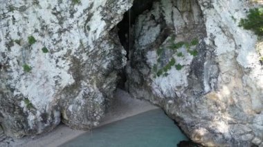 Yunanistan, Korfu, Yaz. Plaj Rovinia, Rovinia 'da kristal berrak suları ve sonsuz mavi gökyüzü ile küçük bir mağarası olan çarpıcı bir plaj. Turistli bir sürü tekne ve uçurumdan atlayan çocuklar.