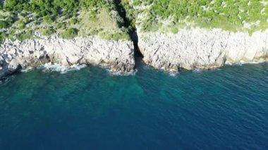 Geçitten bir dron uçuyor. Karadağ 'ın kayalık bir kıyı şeridinde, sadece denizden ulaşılabildiği için ulaşılamayan küçük bir vadi bulunuyor.