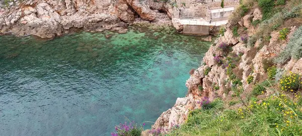 Kristal berrak ve şeffaf denizin üzerindeki eski şehrin kalesinin altındaki yeşil yamaçlar.