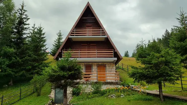 Sessiz ve bereketli bir ormanın kalbine yerleşmiş, ağaçlar ve canlı yeşilliklerle çevrili tuhaf ve küçük bir ahşap ev.