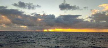 Geniş ve geniş bir su kütlesi, arka planda beliren bulutlu bir gökyüzü eşliğinde büyüleyici bir doğa güzelliği manzarası yaratıyor.