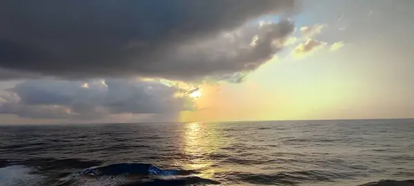 Geniş ve geniş bir su kütlesi, arka planda beliren bulutlu bir gökyüzü eşliğinde büyüleyici bir doğa güzelliği manzarası yaratıyor.