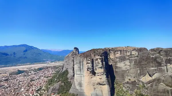 Bu görüntü, çevresindeki doğal güzellikleri gözler önüne seren görkemli dağların ve sarp kayalıkların ortasındaki genişleyen şehrin etkileyici bir hava perspektifini yakalıyor.