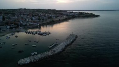 Huzurlu ve sakin bir alacakaranlık sahnesi. Huzur içinde yüzen tekneler ve kıyı boyunca küçük tuhaf bir kasaba.