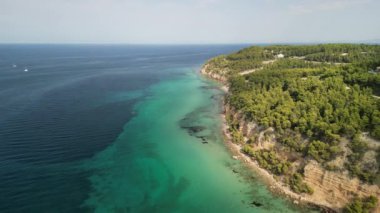Havadan çekilen görüntülerde berrak turkuaz suları ve canlı yemyeşil yeşillikleri olan çarpıcı bir sahil görülüyor.
