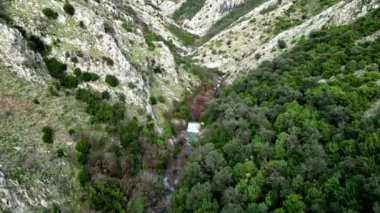 Büyüleyici bir hava görüntüsü güzel bir şekilde sergileniyor yemyeşil bir vadi mükemmel bir şekilde dik dağların arasına kurulmuş.