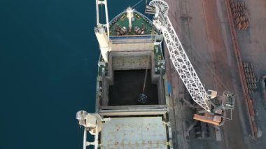 Kıyı vincinin yardımıyla geminin limana boşaltılması. Kargoyla birlikte açık ambar. Yüksek kaliteli FullHD görüntüler