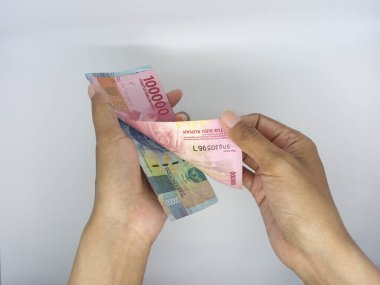 Endonezya para birimi, el ele tutuşma ve para sayma banknotları beyaz arka planda izole.