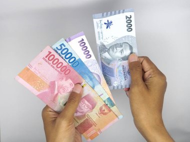 Endonezya para birimi, el ele tutuşma ve para sayma banknotları beyaz arka planda izole.