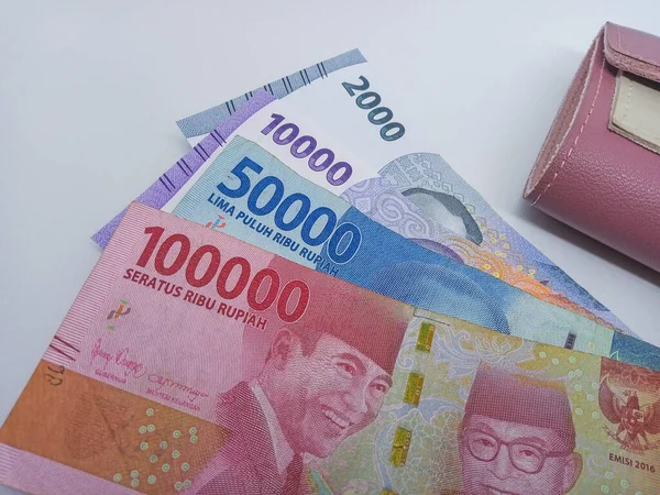 Indonesian currency, rupiah money paper. One hundred thousand, fifty thousand, ten thousand, and two thousand nominal beside wallet isolated on a white background.