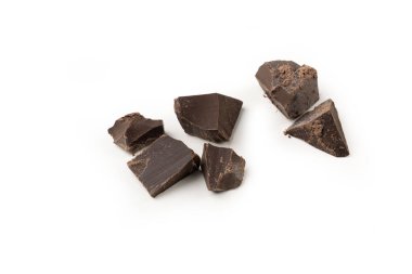 Beyaz arka planda siyah çikolata parçaları. Parçalar şekil ve boyut olarak düzensiz.