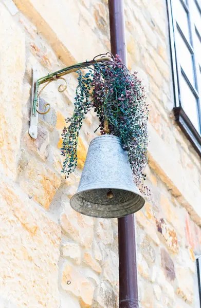 Bir caddeyi süsleyen çiçeklerle süslenmiş metal çan.