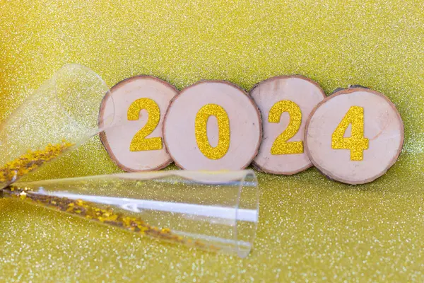 Yeni yıl 2024 altın sayılar altın bir zemin üzerinde altın bir zemin ve şampanya kadehleri 