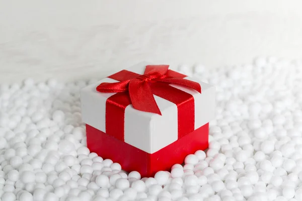 Kırmızı pruvalı hediye kutusu kartopları ve açık arkaplan ile çevrili