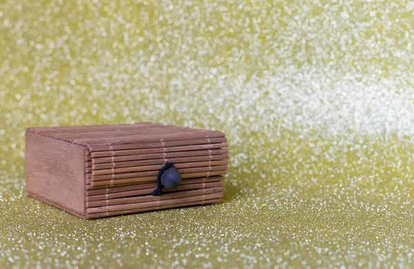 Altın parıltılı arka planda küçük tahta kutu.