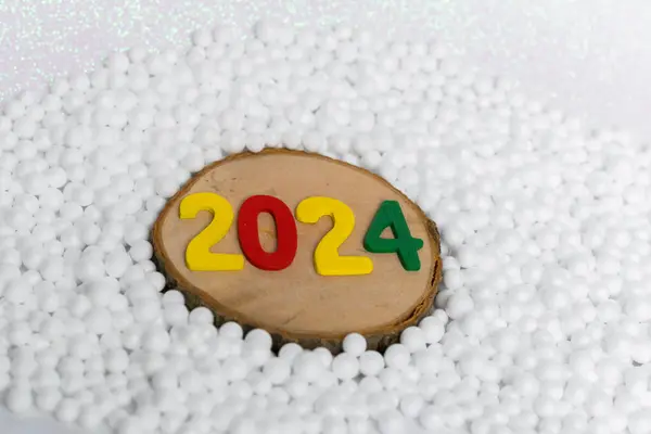 Yeni yıl 2024 Yuvarlak ahşap ve kartopu üzerinde renkli sayılar halinde