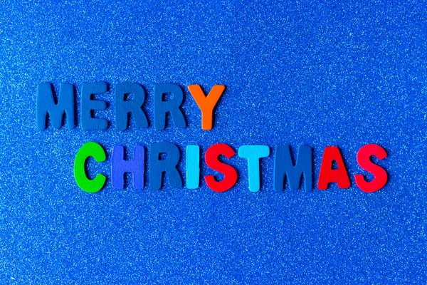 Mavi ve parlak bir arka planda Mutlu Noeller diyen renkli mektuplar.