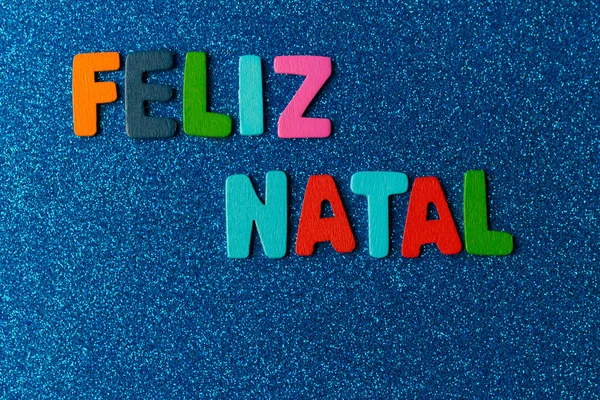 Portekizce Feliz Natal ifadesinin olduğu renkli mektuplar. Mavi arka planda parıltılı, Noel konsepti.
