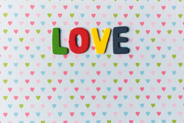Kalplerin arka planında aşk kelimesinin olduğu renkli harfler.
