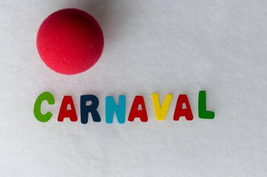 İspanyolca karnaval kelimesinin olduğu renkli harfler ve beyaz bir arka plan ve çalışmak için bir palyaço burnu.