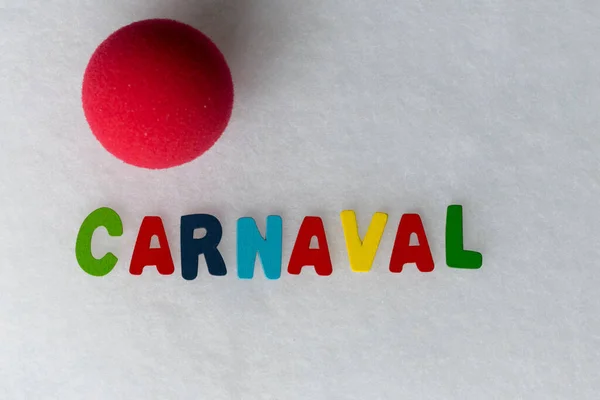 colored letters with the word Carnival in Spanish and an ornamental clown nose on a white background and space to work