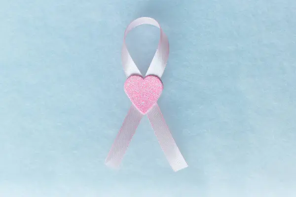 Ortada kalp olan pembe fiyonk, göğüs kanserini temsil ediyor, beyaz bir arka plan ve çalışmak için yer.