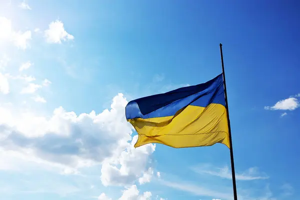 Ukrayna bayrağı dalgalanıyor mavi gökyüzü ve arka planda hafif bulutlar