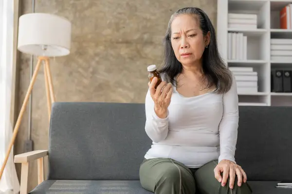 Äldre Ohälsosam Asiatisk Kvinna Som Håller Pillerflaska Och Läser Medicineringsinstruktioner — Stockfoto