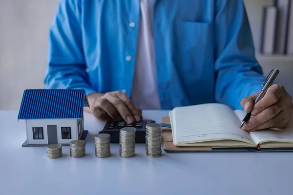 Finance for real estate concept Man calculating notes on book and stack of coins lying on wooden table To fund the purchase of good ideas remote picture