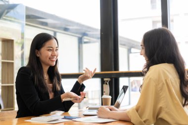 İki kadın Asyalı muhasebeci mali yönetim planlarını tartışıyor. Yeni başlatılan proje fikirlerinin analizi