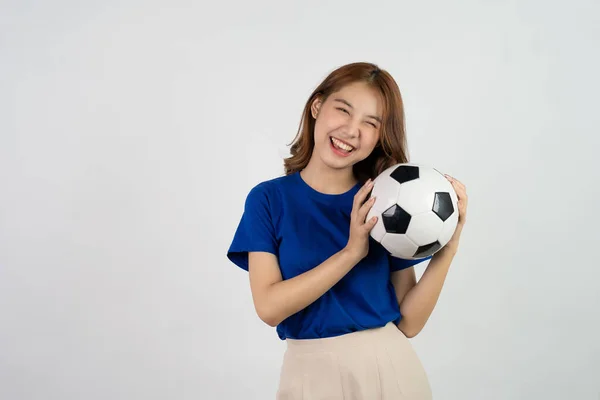 快乐的亚洲女足球迷用足球向最喜爱的球队提供支持 身穿蓝色T恤衫的女人拿着足球在足球比赛中欢呼 被白色背景隔离 — 图库照片