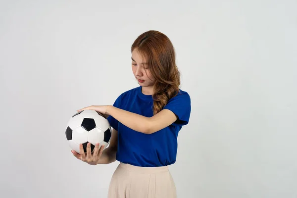 快乐的亚洲女足球迷用足球向最喜爱的球队提供支持 身穿蓝色T恤衫的女人拿着足球在足球比赛中欢呼 被白色背景隔离 — 图库照片