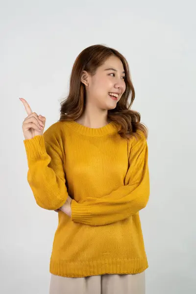 兴奋的亚洲女人在孤立的背景下举手表决 促销广告的概念快乐的少女穿着黄色衬衫站在白色房间里 — 图库照片