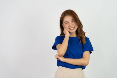 Neşeli, arkadaş canlısı, iddialı, açık mavi tişört giyen genç Asyalı kız, rahat, tasasız, beyaz bir arka plana karşı poz veriyor..