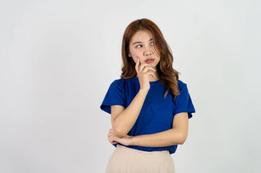 Neşeli, arkadaş canlısı, iddialı, açık mavi tişört giyen genç Asyalı kız, rahat, tasasız, beyaz bir arka plana karşı poz veriyor..