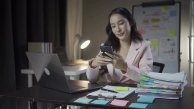 Meşgul Asyalı iş kadını proje belgeleri üzerinde çalışıyor. Bilgisayarla konuşuyor, modern ofis finans sektörü kavramında uzaktan çalışıyor.